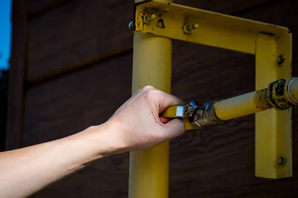 Adam elini gaz kapatmak için kapak üzerinde tutuyor. Adam balkondan kapatır.