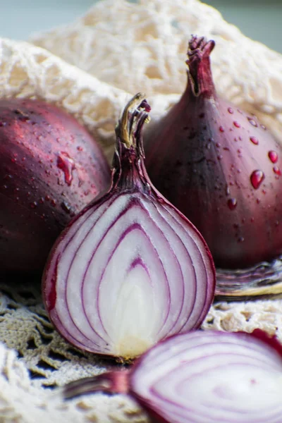 Red onion and red onion slices on wooden cutting board.