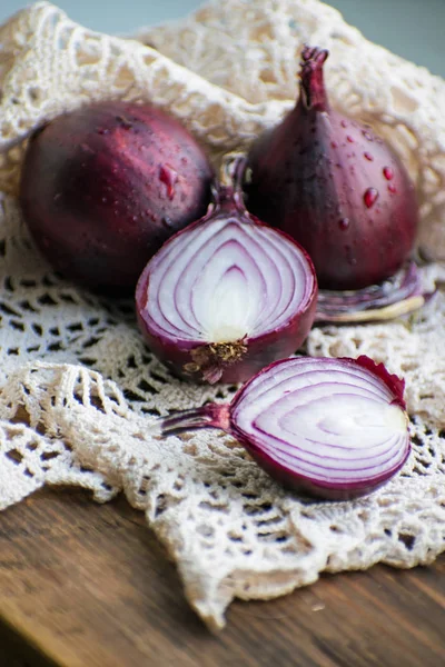 Red onion and red onion slices on wooden cutting board.