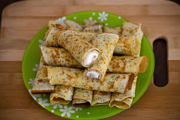 Pancakes rolls with cottage cheese. Pancakes with cheese on a wooden board. Maslenitsa.