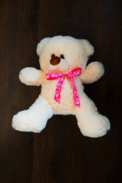 Cute teddy bear on wooden background. Fluffy teddy bear with a pink bow. A gift to the child for the holiday. Valentine\'s Day Gift.