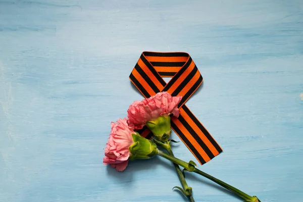 Carnation and St. George ribbon on blue background, symbol of the great Victory, victory day, 9 May background