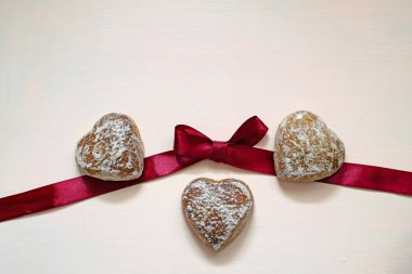 Bordo kurdele ile pembe arka plan üzerinde beyaz sır zencefilli kurabiye.