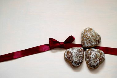 Bordo kurdele ile pembe arka plan üzerinde beyaz sır zencefilli kurabiye.