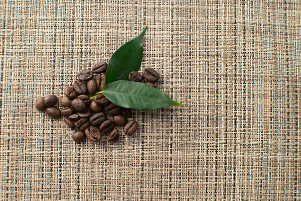 Кофейные зерна Арабика с листьями на коричневом фоне — стоковое фото