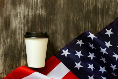 Eski ahşap arka plan üzerinde Amerikan bayrağı ve kahve kağıt fincan.