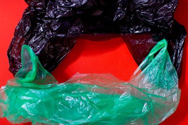 Kırmızı arka plan üzerinde iki renkli tek kullanımlık çöp torbaları.