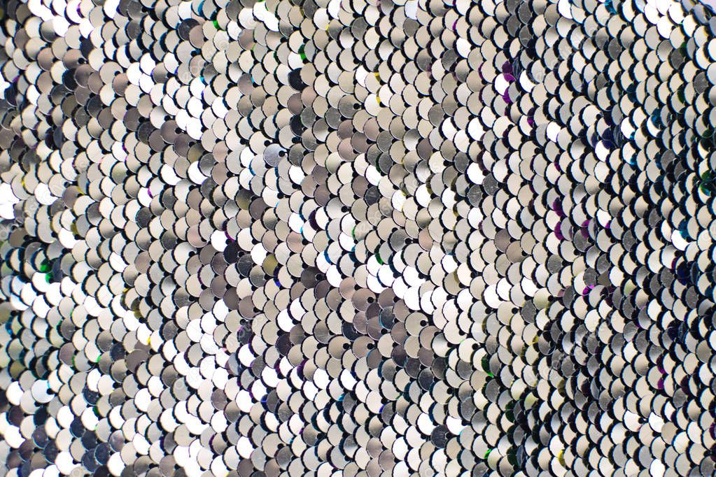 Pieces of cloth with silver sequins. Glitter background. Sequin texture