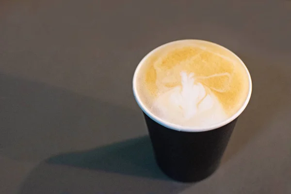 Xícara de cappuccino com um padrão na espuma no fundo cinza . — Fotografia de Stock