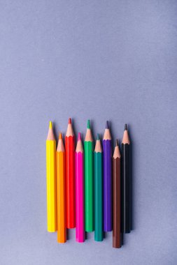 Gri arka planda çok renkli bir kalem. Renkli kalemler bir sırada yatıyor. Okul için kalemler.