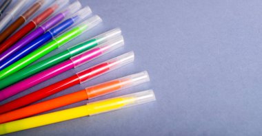 Gri arkaplandaki çok renkli keçeli kalemler veya işaretler.