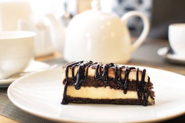 Kahve masasında beyaz tabakta lezzetli çikolatalı tiramisu dilimi. Geleneksel İtalyan bisküvisi ya da pasta.