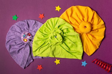 Üç sevimli çocuk saç bandı ya da mor arka planda türban.