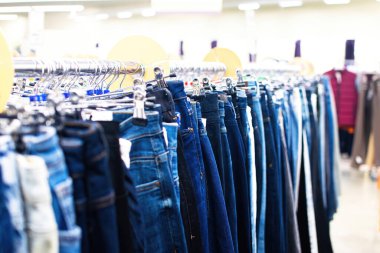 Mağazadaki askıda bir dizi kadın pantolonu. Mağazada kot pantolon satışı. Seçici odak.