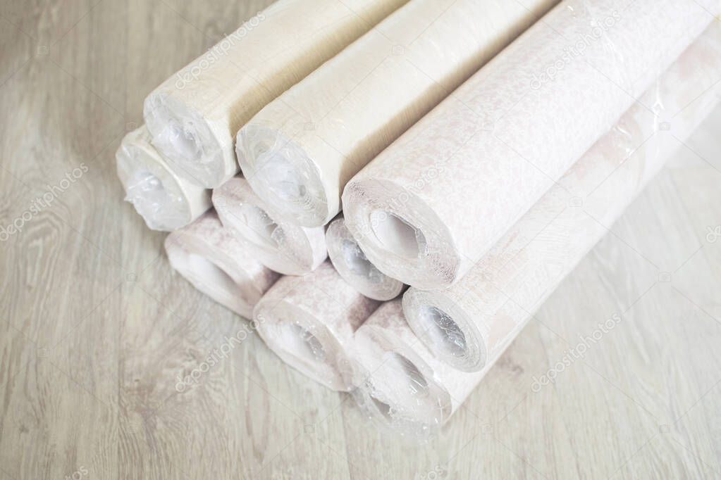 Several rolls of pastel paper wallpaper for wall renovation. Paperhangings on the floor. Wallpaper or paperhangings delivery.