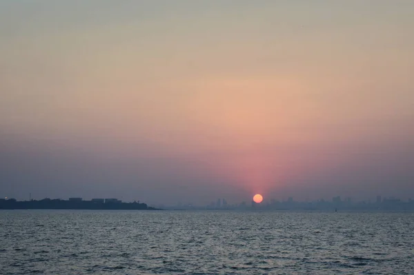 Mumbai kıyısındaki büyük binaların arkasında güneş batıyor..