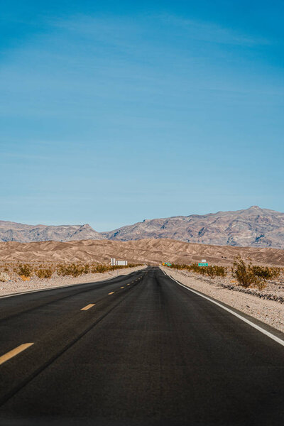 Dark wavy highway in the desert. Highway in Death Valley amid a desolate brown landscape