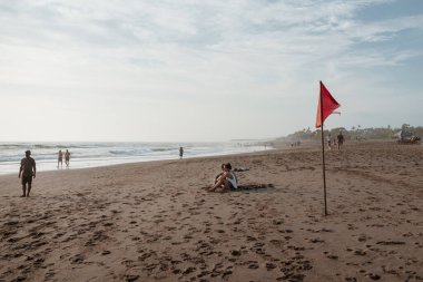 Canggu 'da kumsalda gün batımında insanlarla ve küçük dalgalarla. Batu Bolong plajı Bali