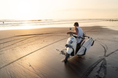  Güzel gün batımında bir adam kumsalda bisiklette oturuyor. Bisiklette oturan bir adamın aynadaki yansıması, Canggu, Bali
