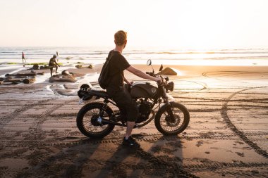 Güzel gün batımında bir adam kumsalda bisiklette oturuyor. Bisiklette oturan bir adamın aynadaki yansıması.