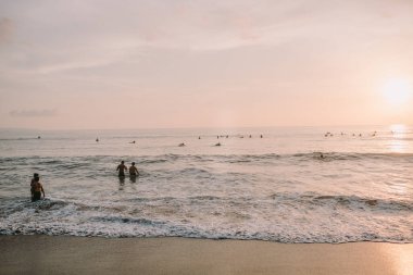 Canggu 'da kumsalda gün batımında insanlarla ve küçük dalgalarla. Batu Bolong plajı Bali