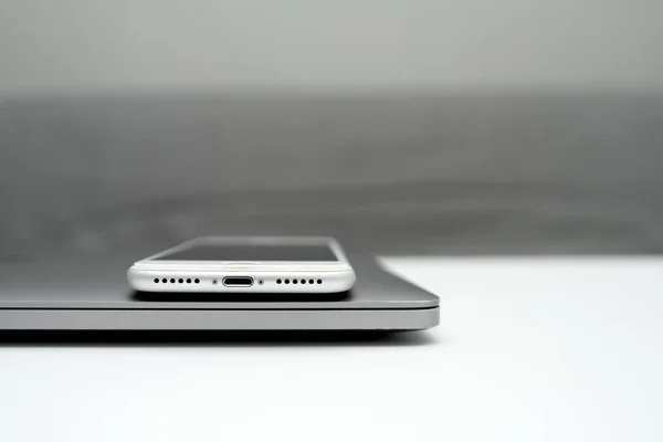 Çelik bir dizüstü bilgisayarda beyaz bir telefon var. Serbest konsept