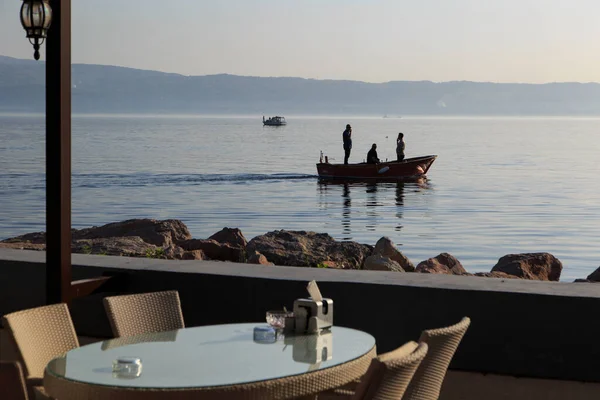 9 Kasım 2019. Deniz manzaralı bir açık kafe ve teknede balıkçılar. İzmit Körfezi, Kocaeli, Türkiye.
