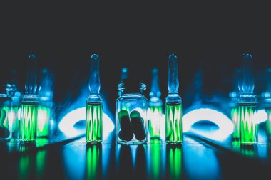 concept of doping in sport. Bright ampoules with luminous green contents: Diuretics, Peptide hormones, Anabolic steroids, Painkillers, Stimulants. artistic dark filter. low key photo clipart
