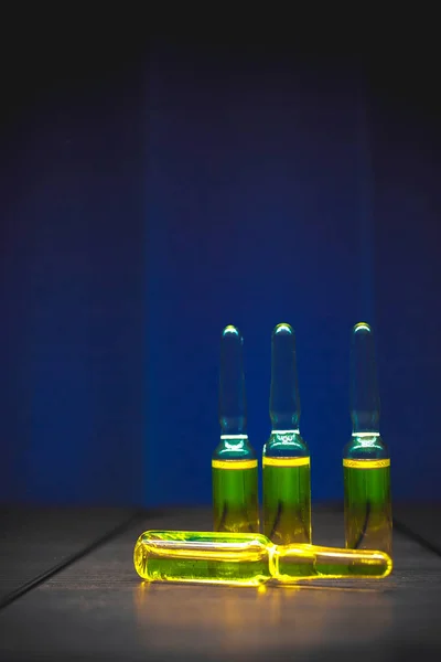 Żółty odurzających, substancji chemicznych, witamin w ampułkach na niebieskim tle. Artystyczny ciemny filtr. niski klucz zdjęcie — Zdjęcie stockowe