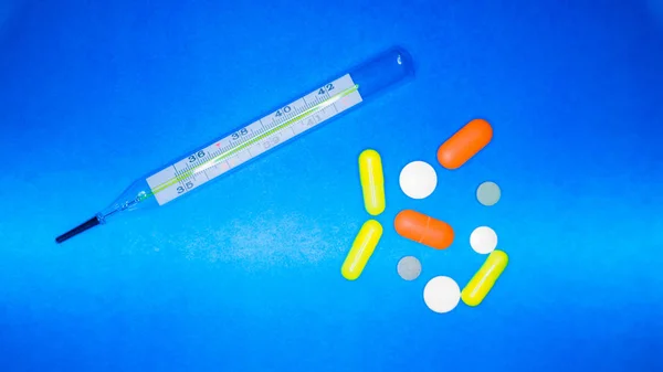 Medische achtergrond. Thermometer, pillen op een blauwe achtergrond. Geneeskunde, gezondheidszorg, griep concept. Lange webindeling — Stockfoto