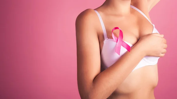 Giovane donna che esamina il seno alla ricerca di noduli o segni di cancro al seno. Nastro rosa — Foto Stock