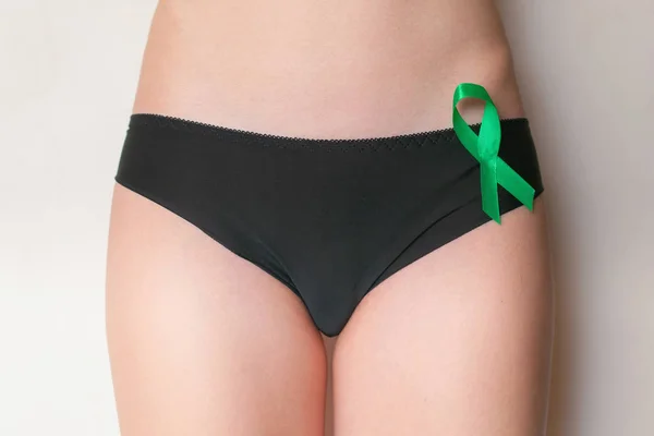 여성 팬티-녹색 리본을 잡고 볼을 닫습니다. 난소 암 및 부인과 질환 개념 스톡 이미지