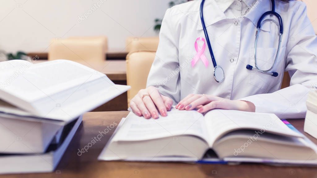 Female doctor with pink ribbon, medical student for textbooks. Protocols for diagnosis and treatment of breast cancer.