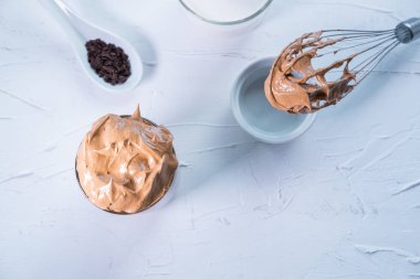 Beyaz arka planda çırpılmış kahve ve çikolatalı Kore dalgona kahvesi. Üst Manzara. Düz yatıyordu.