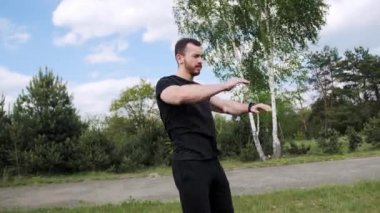 Sakallı yakışıklı sporcu ısınıyor, kollarını stadyumda sallıyor..