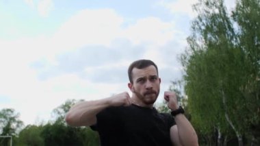 Sakallı çekici bir boksör dışarıda hayali bir rakiple yumruk atıyor..