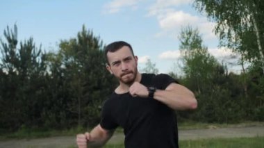 Çekici, güçlü ve sakallı bir boksör dışarıda hayali bir rakiple yumruk atıyor..