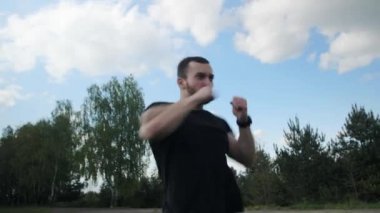 Sakallı çekici kaslı boksör dışarıda hayali bir rakiple yumruk atıyor..