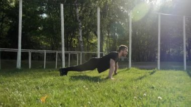Sakallı güçlü kaslı atlet ısınıyor, genç sporcu yerden sıkıyor..
