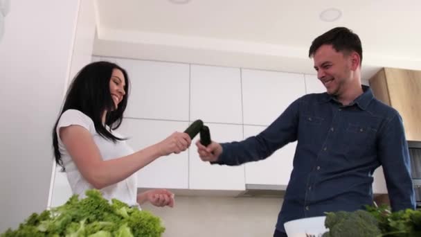 Casal jovem se divertindo na cozinha moderna.Legumes em primeiro plano . — Vídeo de Stock
