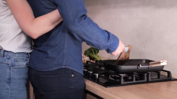 Pareja joven preparando la cena y abrazándose en la cocina moderna blanca . — Vídeos de Stock