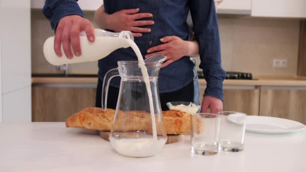 Un uomo versa il latte in un decanter sul tavolo della cucina . — Video Stock