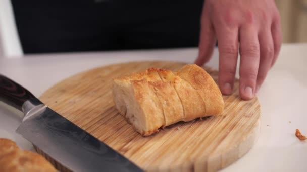 Een man legt gesneden stokbrood stukken op een witte plaat. — Stockvideo