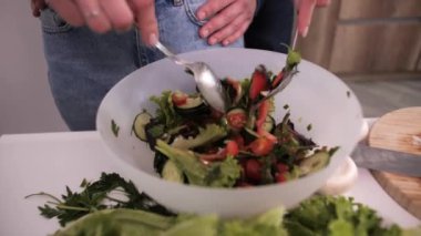 Kız sebzelerin salatasını karıştırıyor, mutlu genç çift sevgiyle sarılıyor..