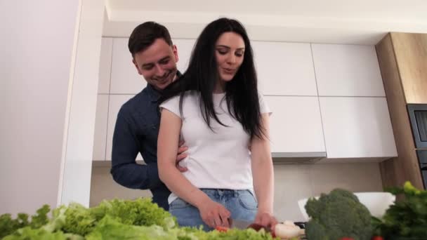 Férj és feleség készít saláta a modern fehér konyha tánc közben. — Stock videók