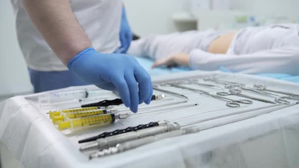 De chirurg neemt het instrument en bereidt een incisie in de buik voor op verdere liposuctie in de operatiekamer.. — Stockvideo
