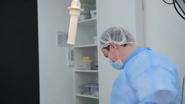 Jonge chirurg neemt instrument en bereidt zich voor op een incisie in de buik voor verdere liposuctie in de operatiekamer. — Stockvideo