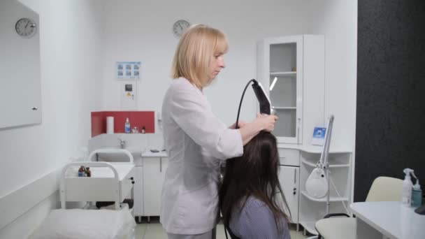 Trycholog przeprowadza analizę włosów na głowie pacjenta w klinice kosmetologicznej.. — Wideo stockowe