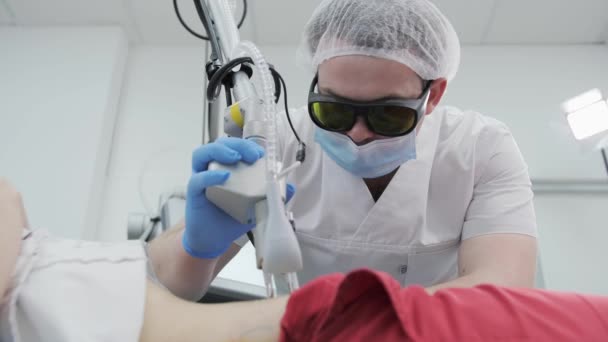 Jonge mannelijke chirurg maalt een litteken op de buik in de operatiekamer met een laser in een kosmetologische kliniek. — Stockvideo