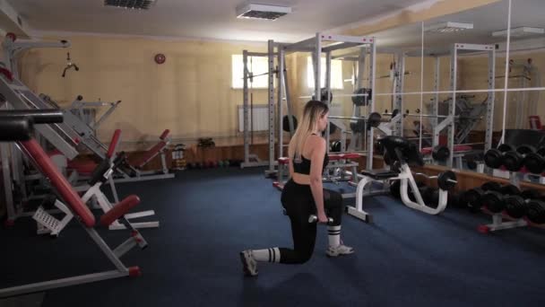 Athletic blonde makes lunges with dumbbells in the gym. — Stock Footage Athletic blonde makes lunges with dumbbells in the gym. Royalty Free Stock Footage